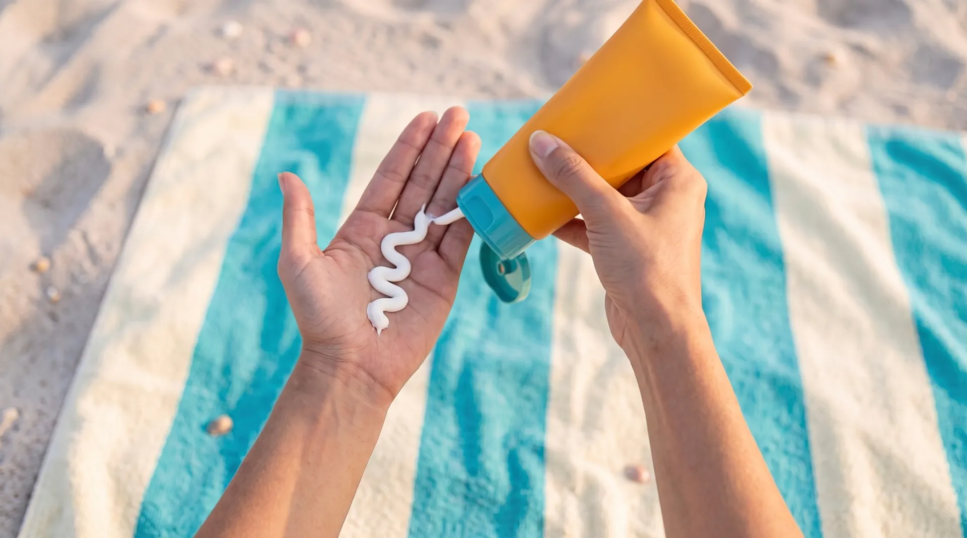 A wave of thick white cream squeezed from the tube onto an open palm, over the striped towel