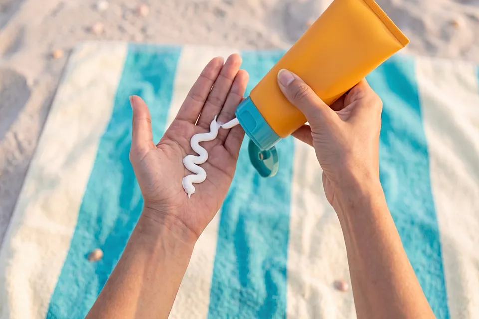 A wave of white cream on an open palm, the tube over it