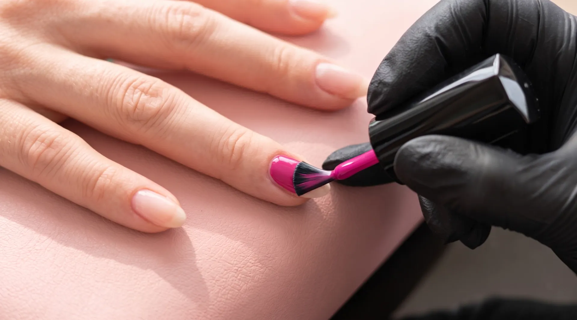 The brush fans out on a bare fingernail and leaves a glossy coat of fuchsia behind it