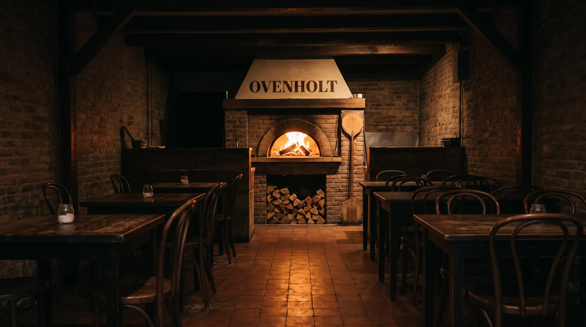 A dark pizzeria before opening: tables on both sides of the aisle, a brick oven with a burning fire and the sign Ovenholt at the far end