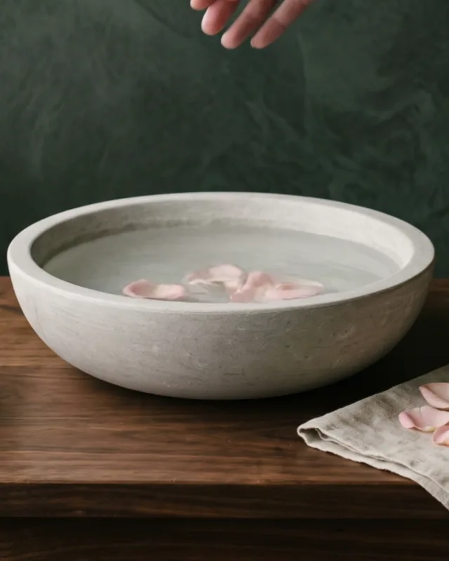 Rose petals floating in a stone bowl of water