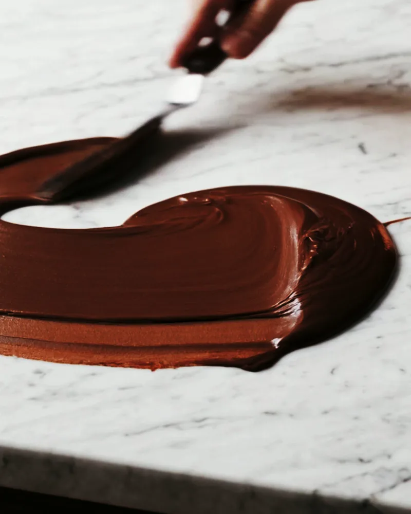 A palette knife draws dark chocolate over the marble in waves